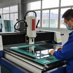 Technician using a glass cutting machine in a modern workshop.